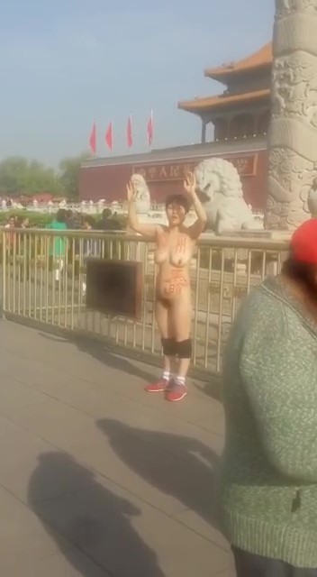 一妇女全裸在天安门前抗议，身上写着“黑暗”两字
